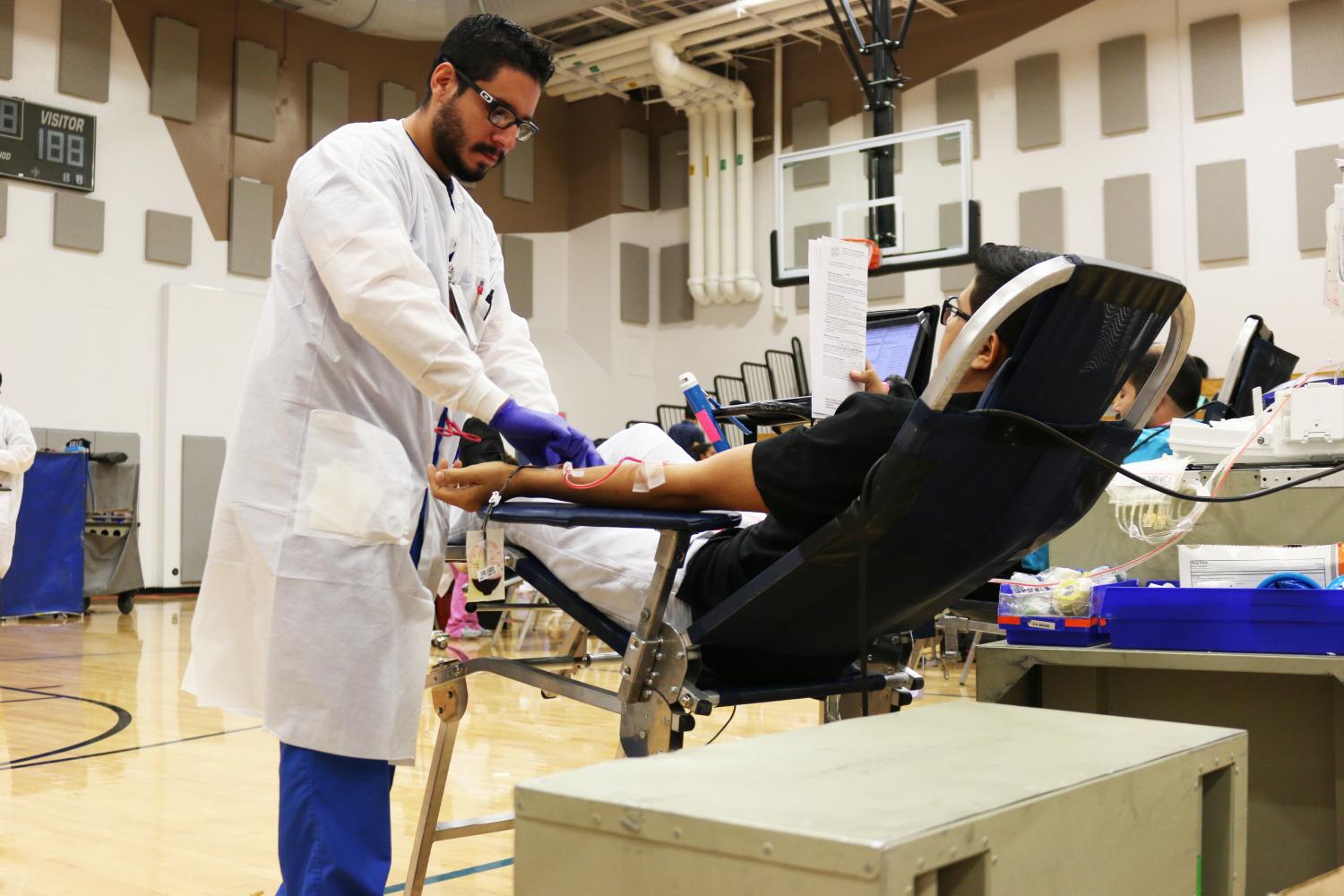 A doctor part of the blood drive takes a blood sample from a student early Tuesday morning Sept. 12 in the auxiliary gym. 